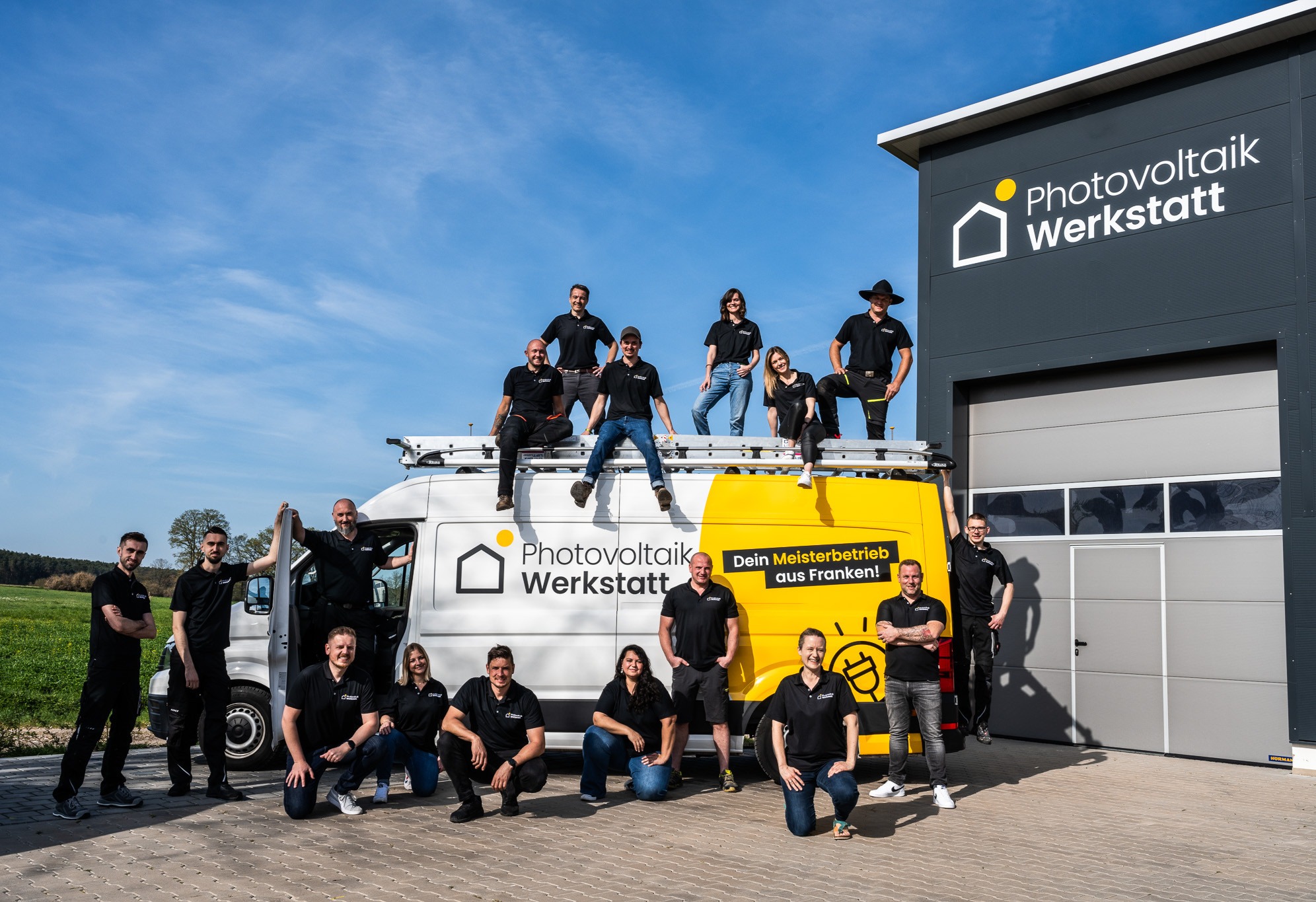 Gruppenfoto vor einem Firmengebäude und einem Servicefahrzeug der Photovoltaik Werkstatt