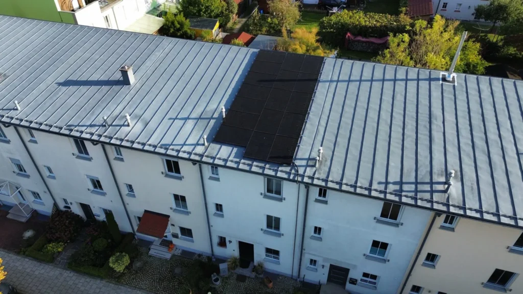 Luftaufnahme eines Mehrfamilienhauses mit geneigtem Dach, vorbereitet für eine Photovoltaikanlage.