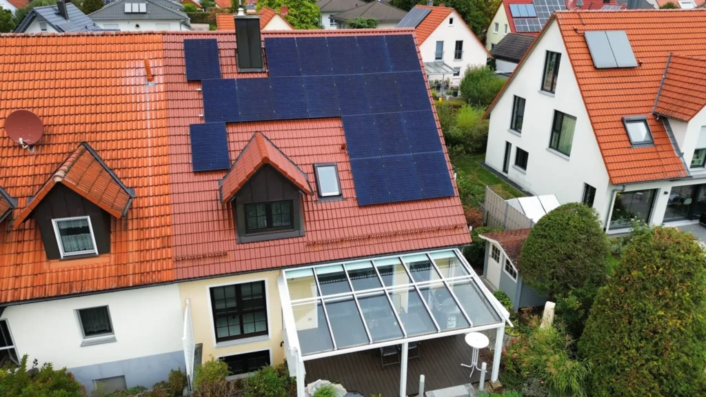 Luftaufnahme eines Wohnhauses mit rotem Ziegeldach und installierter Photovoltaikanlage