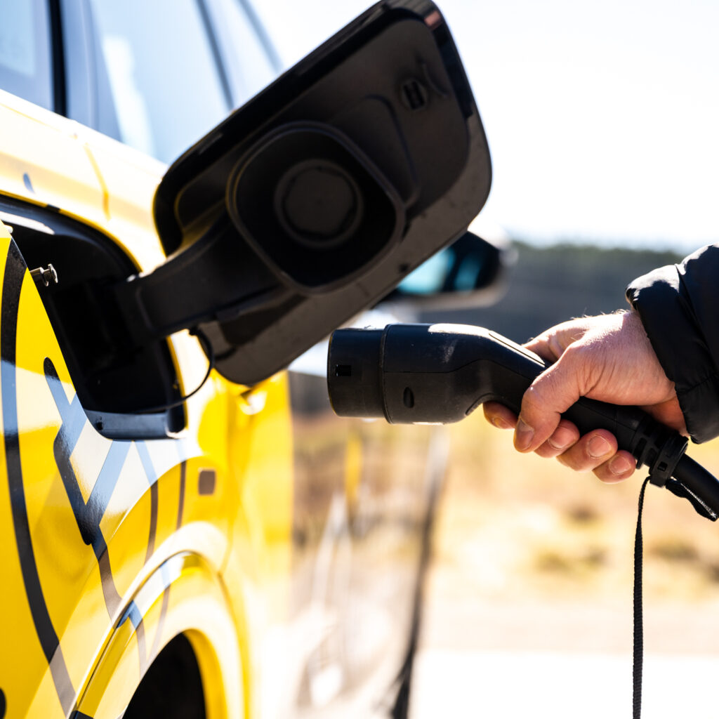 Ein Mann steckt einen Ladestecker in ein Elektro Auto