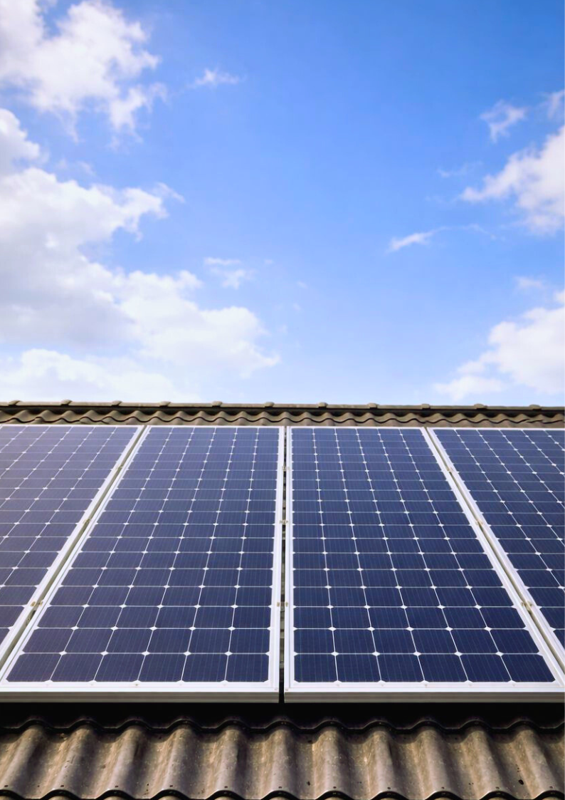 Photovoltaikanlage auf einem geneigten Hausdach mit Solarmodulen unter blauem Himmel.